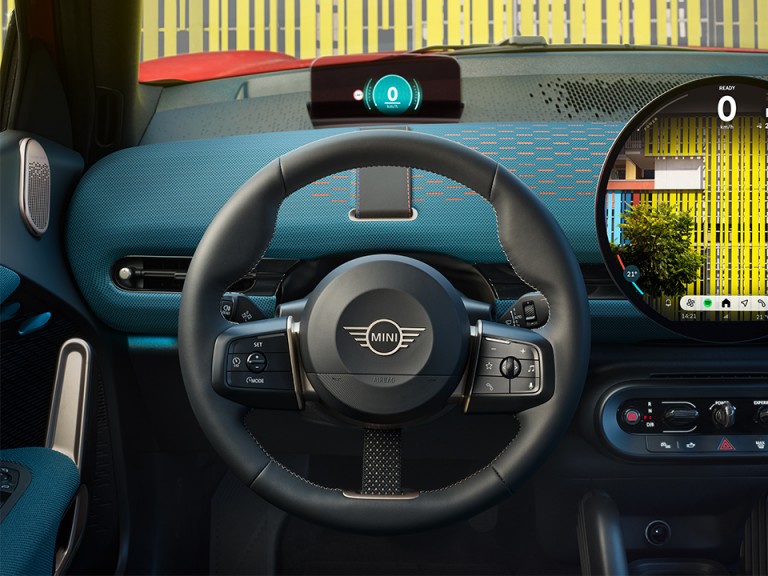 Close-up shot of the new MINI Aceman’s steering wheel and round OLED display, taken from the drivers’ point of view.