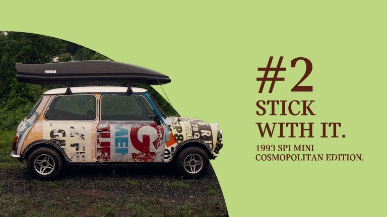Side profile of a 1993 SPi Mini Cosmopolitan Edition wrapped in a selection of stickers and posters and topped with a black roof box, titled “#2 Stick with it.”