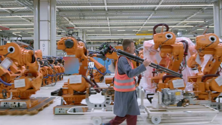 Video that shows Alastair Philip Wiper in an orange high-vis safety vest and carrying his camera equipment past rows of orange robots.