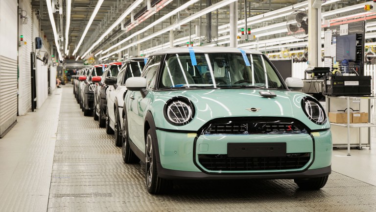 Overhead factory lighting glints off the new MINI Cooper in Ocean Wave Green as it comes down the Plant Oxford production line.